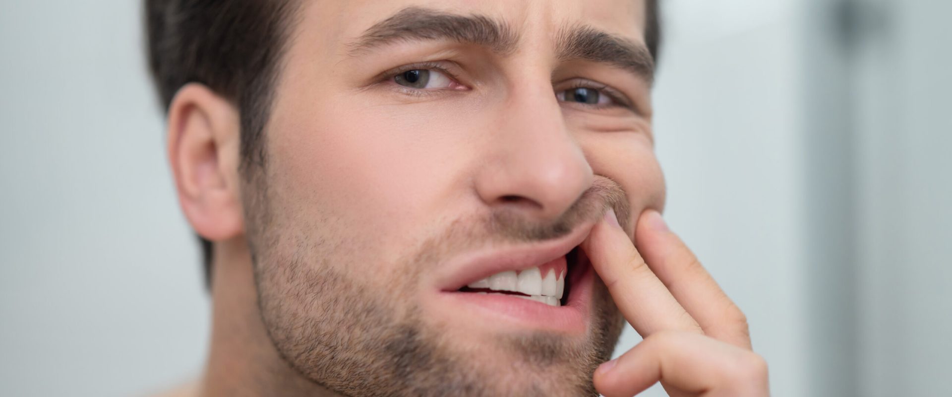 Dental problems. Man checking his teeth and looking disturbed